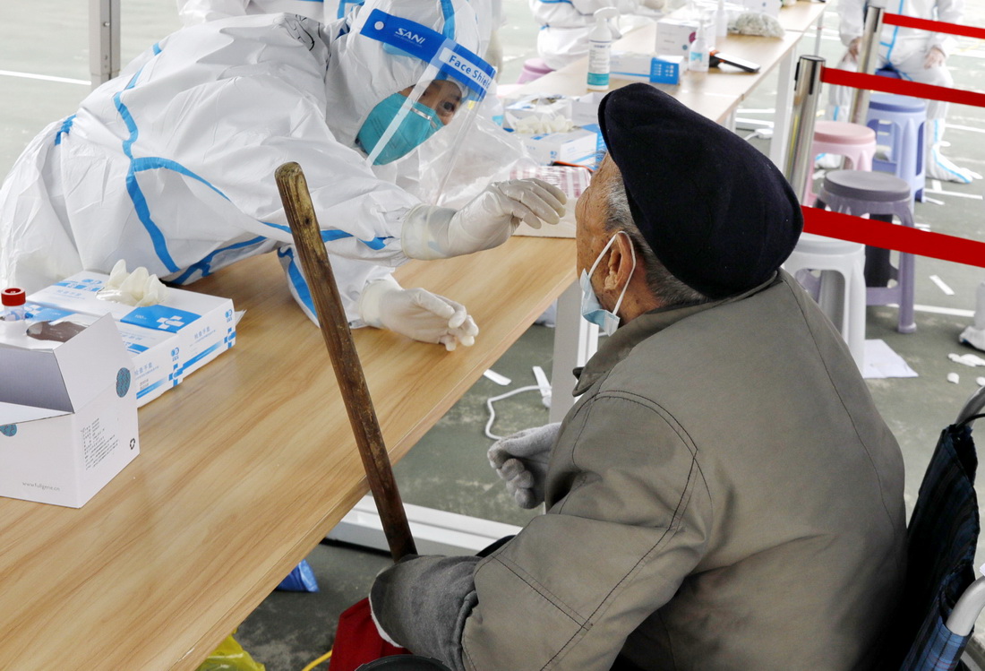 3月28日，在上海市金山区吕巷镇一核酸检测点，医护人员在为一位老人做核酸采样。