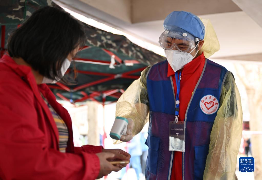 4月4日，在海口市琼山区一个封控居民小区内，志愿者为居民测量体温。