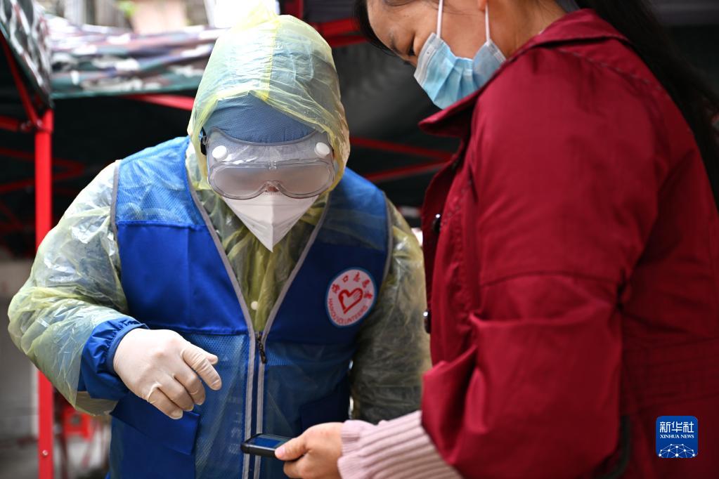4月4日，在海口市琼山区一个封控居民小区内，志愿者引导居民进行核酸检测。