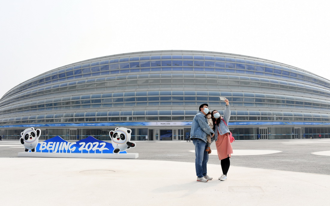 建設者張博偉（左）與家屬在國家速滑館“冰絲帶”外合影留念（4月10日攝）。