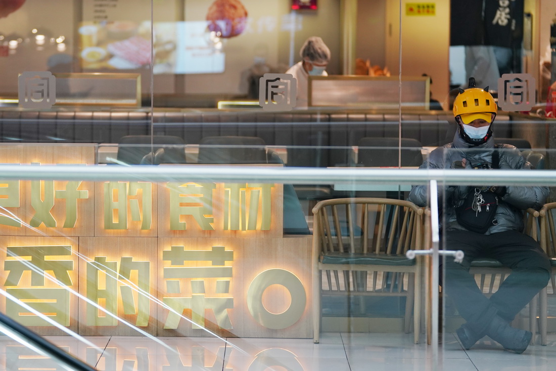 4月11日，在哈爾濱市香坊區一商業廣場內，一名外賣送餐員在餐飲區等待取餐。新華社記者 王建威 攝