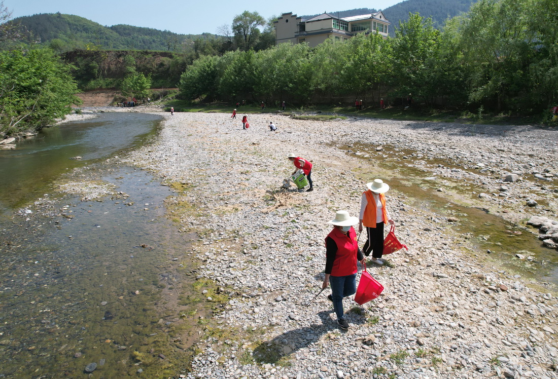 4月10日，女子志願護河隊隊員在陝西旬陽市雙河鎮高坪社區河邊撿拾垃圾(無人機照片）。新華社記者 邵瑞 攝