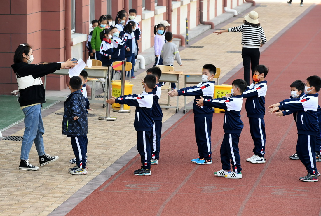 4月11日，青島樺川路小學老師指導學生保持間距排隊。