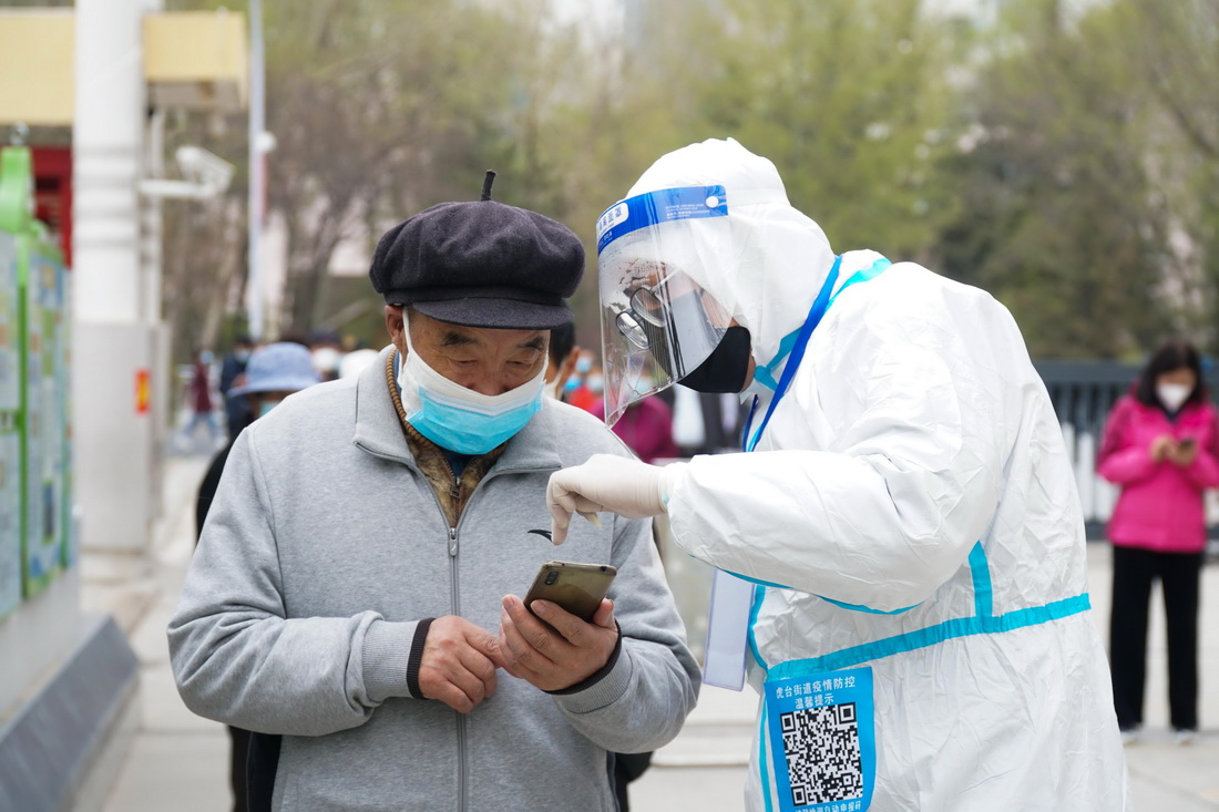 4月15日，在青海省西宁市城西区行知小学核酸检测采样点，工作人员帮助老人完成手机扫码和登记。新华社记者 张子琪 摄