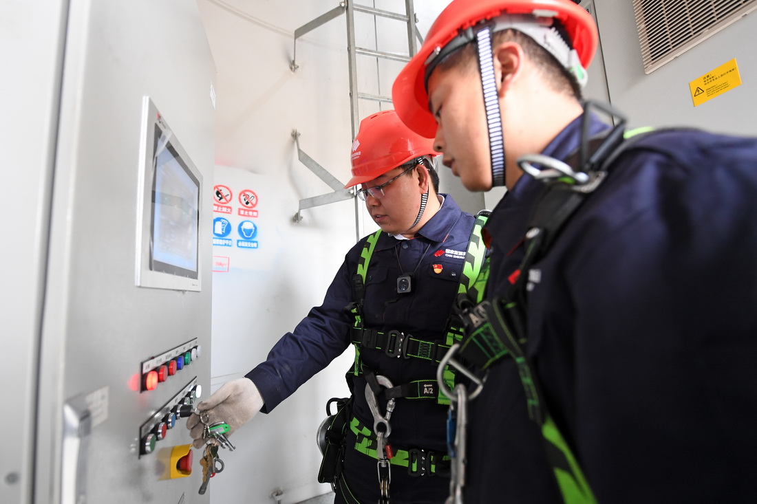 劉彥波（左）和同事胡眾銀在登塔前對風電機組內設備進行調試（4月13日攝）。