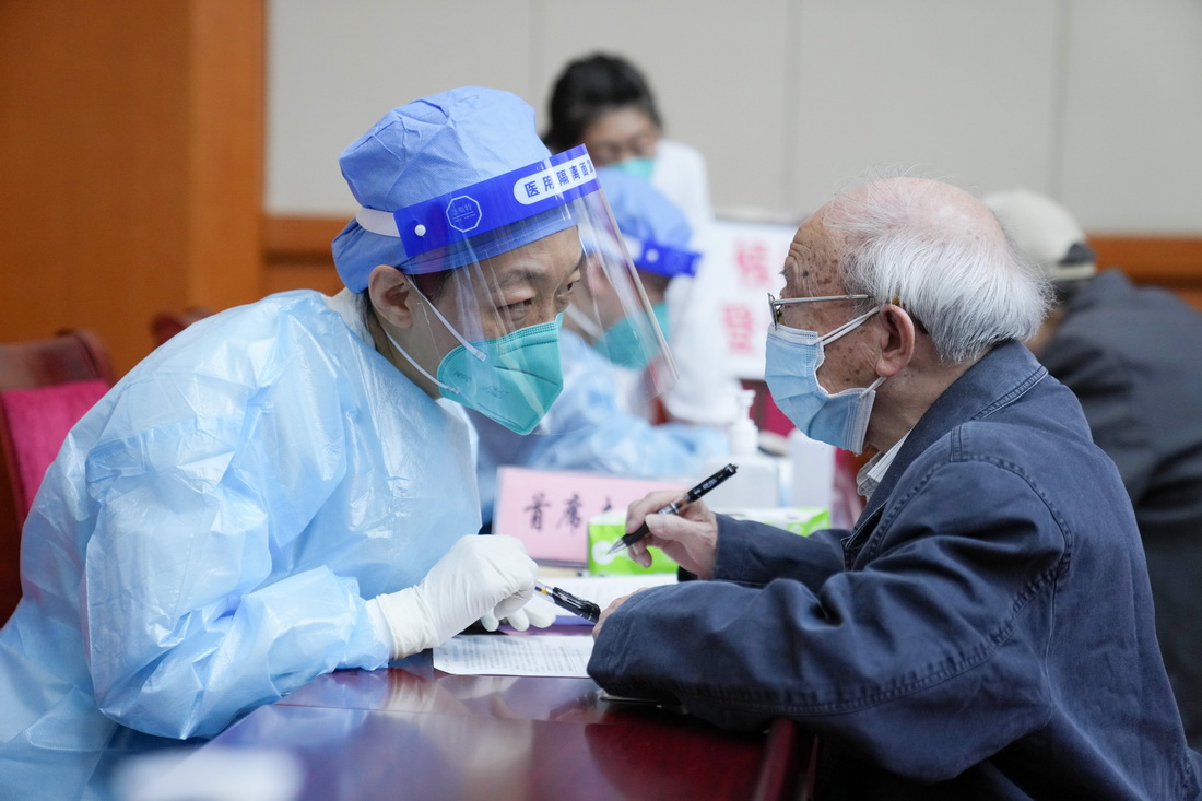 4月18日，医护人员为老年人讲解新冠病毒疫苗接种知情同意书。