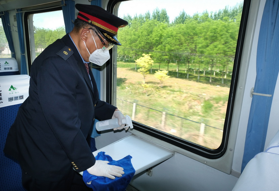 5月1日，鐵路天津客運段乘務員牛鳴泉正在對列車小桌進行消毒作業。