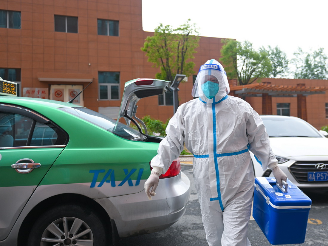 5月14日，王振民把核酸檢測樣本轉運到目的地后，准備交給負責接收樣本的工作人員。新華社記者 張龍 攝