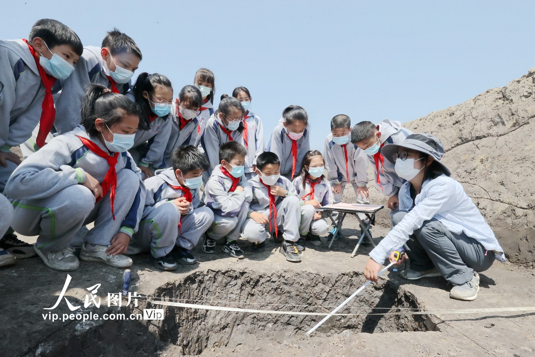 2022年5月17日，在浙江省湖州市德清县雷甸镇杨墩村中初鸣制玉作坊遗址群挖掘现场，考古工作者向学生讲解考古发掘知识。