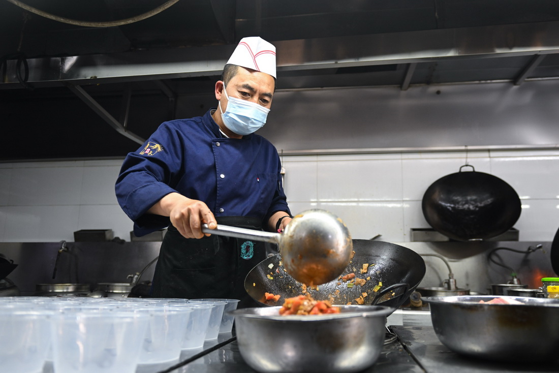 5月19日，朱希明在自家餐馆的厨房里为疫情防控工作人员制作“爱心餐”。新华社记者 张龙 摄
