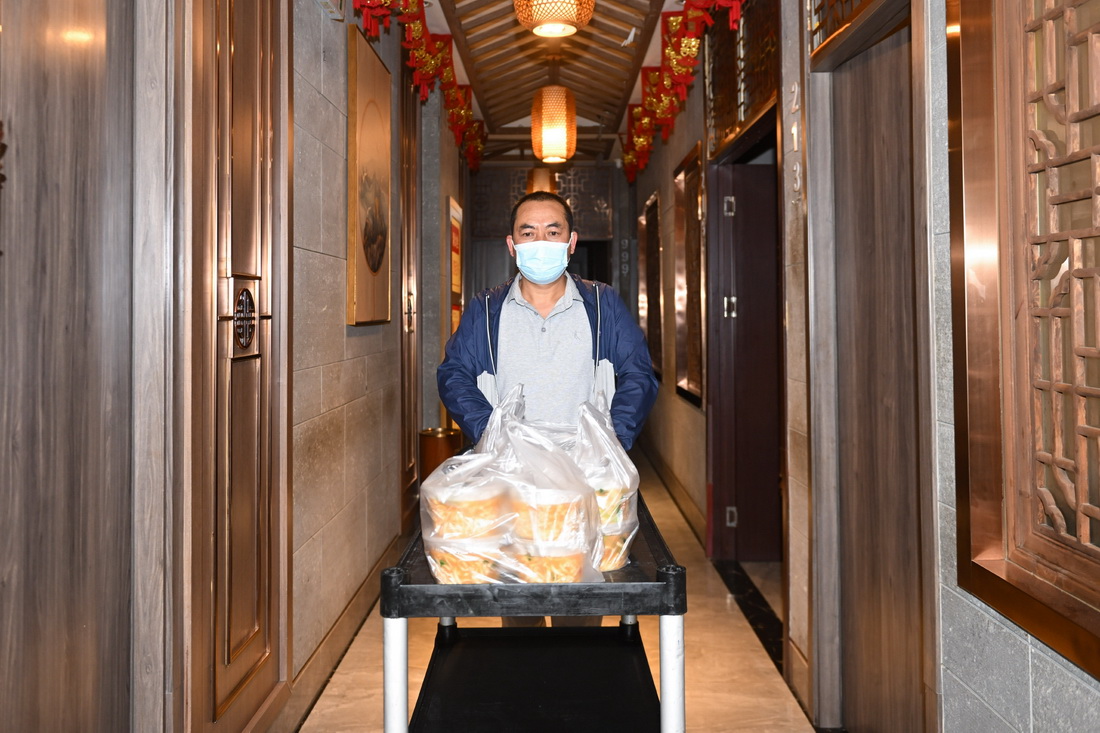 5月19日，朱希明将包装好的盒饭送到餐馆门口。新华社记者 张龙 摄