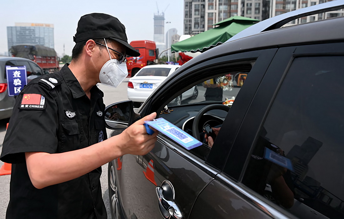 在西安绕城高速高新收费站，工作人员对挡风玻璃上放置有“车辆待查提示牌”的市外行程车辆进行陕西一码通、行程码查验（5月20日摄）。