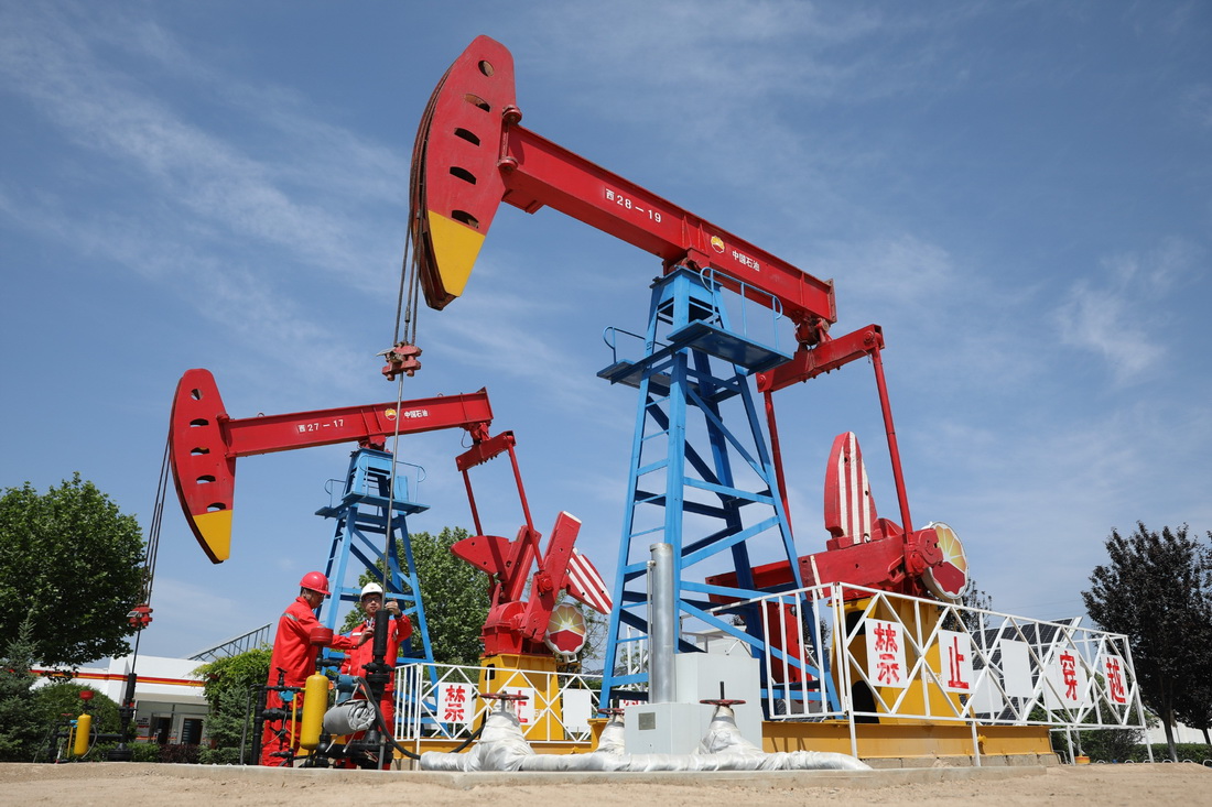 5月24日，长庆油田采油二厂职工在采油井场查看抽油机生产运行情况。新华社记者 杜哲宇 摄