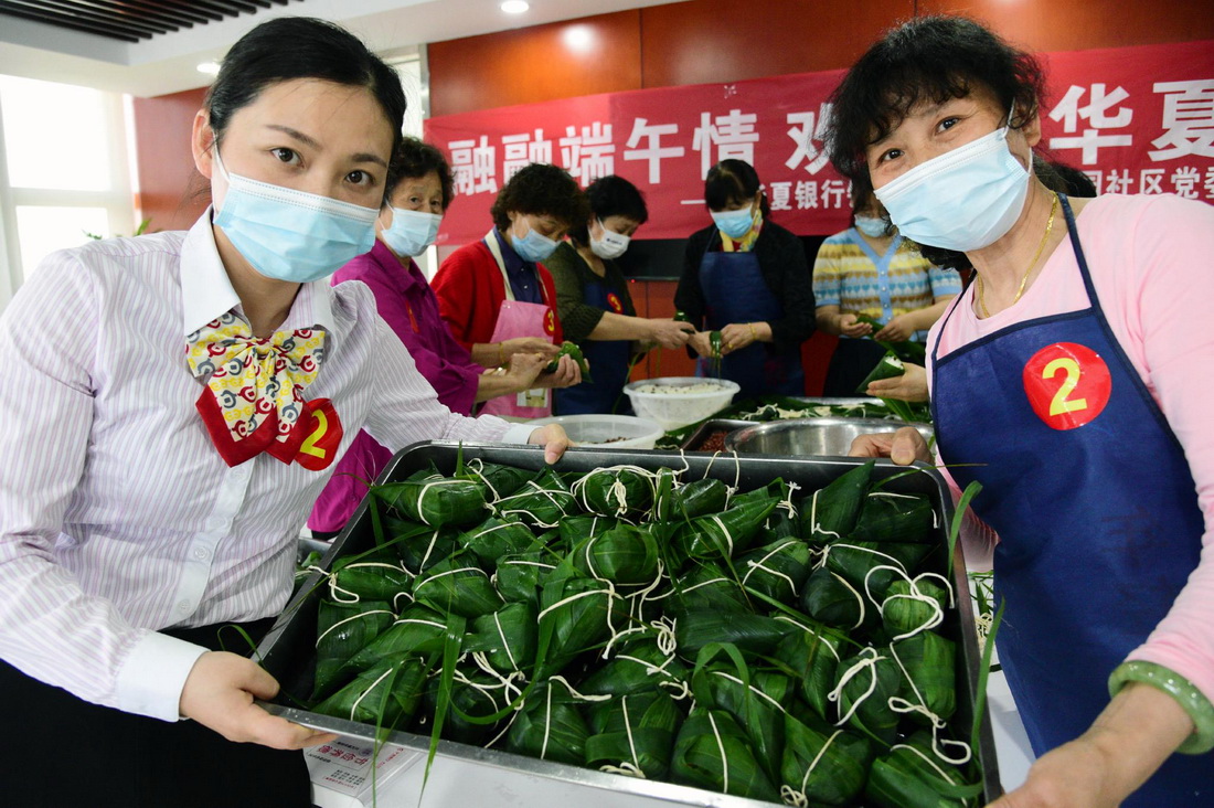 5月25日，江蘇省鎮江市潤州花園社區居民和志願者在包粽子比賽中展示包好的粽子。新華社發（石玉成 攝）