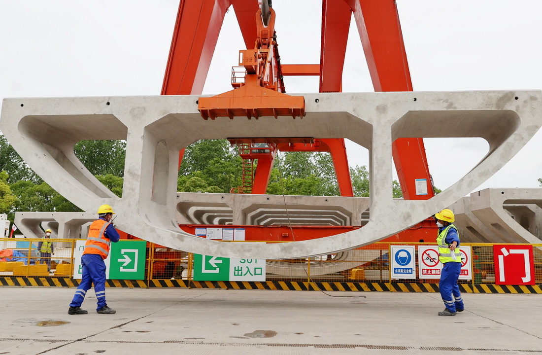5月28日，在中铁隧道局机场联络线11标段施工现场，工人在辅助龙门吊对弧形件进行定位。