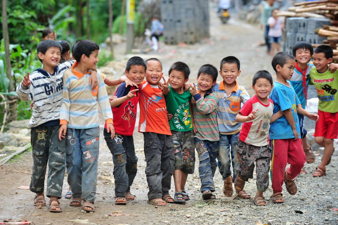 2012年5月30日，渔洞小学的孩子们在学校门口的通村公路上玩耍。那时，通村公路还是砂石路。