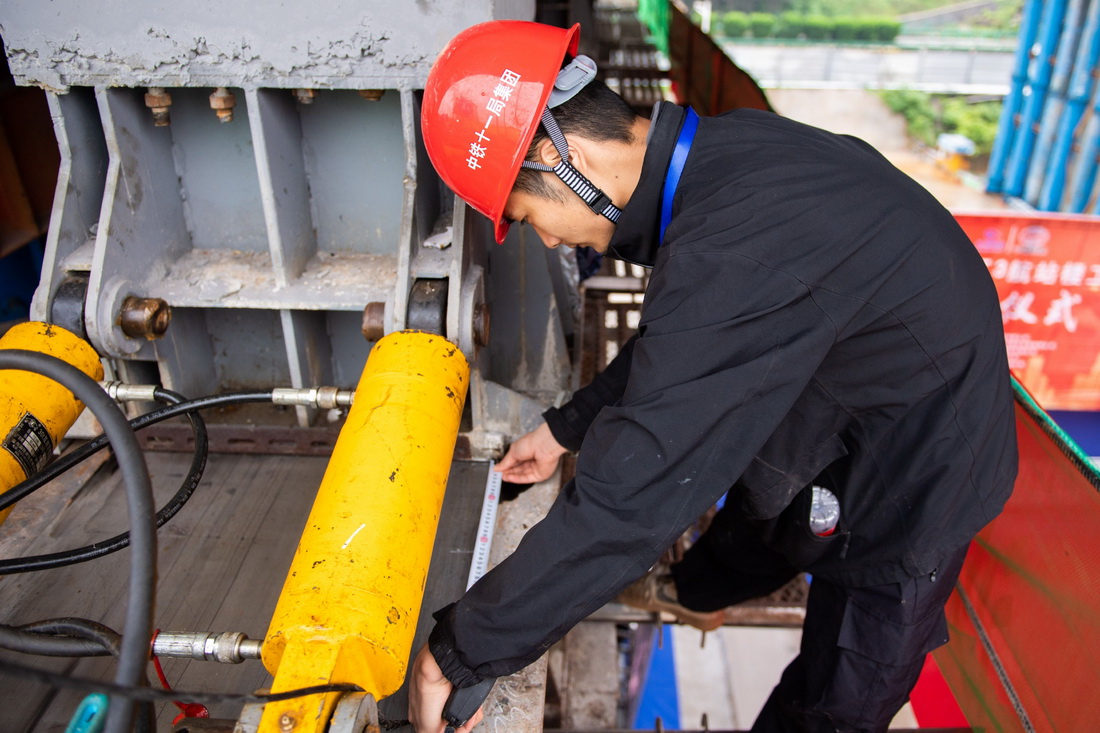 5月29日，在长沙磁浮东延线接入T3航站楼工程道岔梁顶推现场，工作人员测量顶推距离。