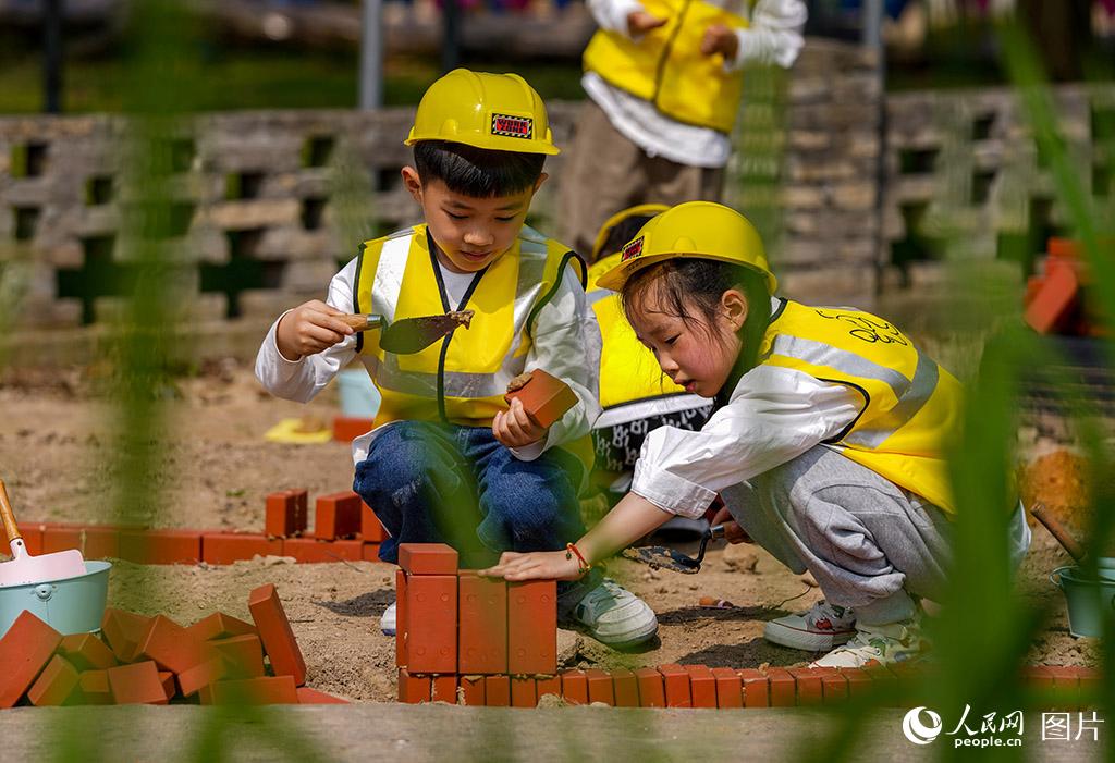 5月27日，浙江省慈溪市周巷鎮天元實驗幼兒園，孩子們在體驗模擬建筑工地施工。當日，幼兒園舉行“野玩節”迎“六一”活動。讓孩子們足不出戶就能體驗“微勞作”。人民網 章勇濤攝