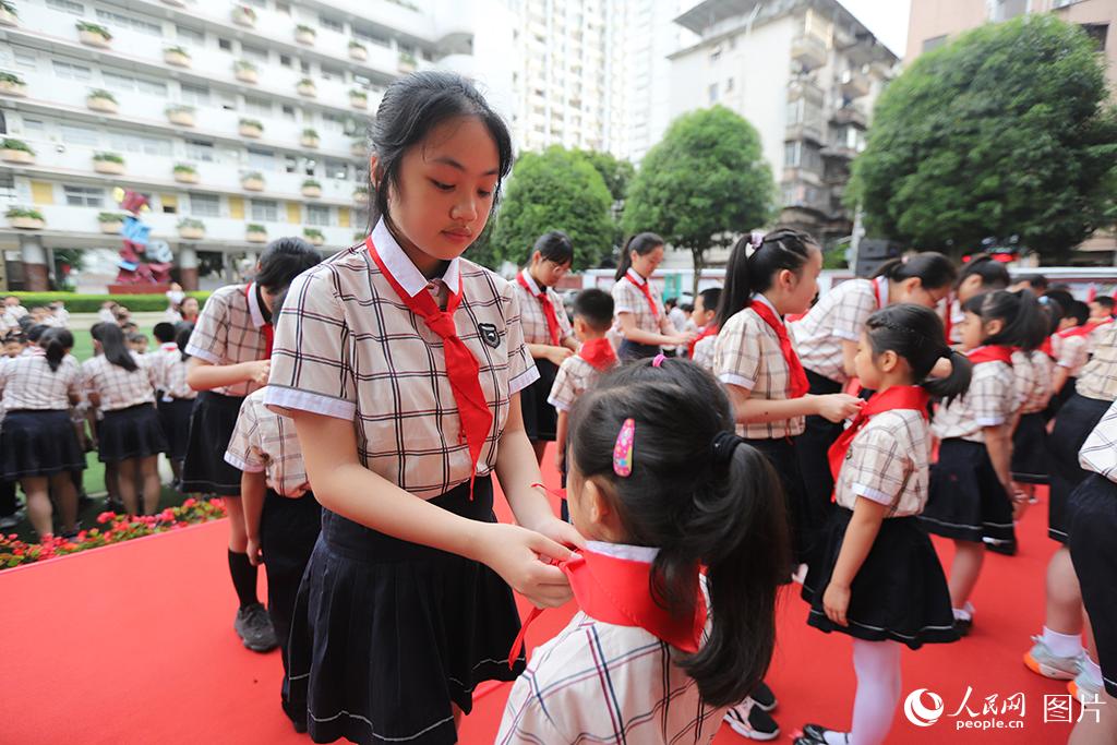 5月31日，在廣西壯族自治區南寧市民主路小學，高年級同學在為新隊員佩戴紅領巾。人民網記者 嚴立政攝