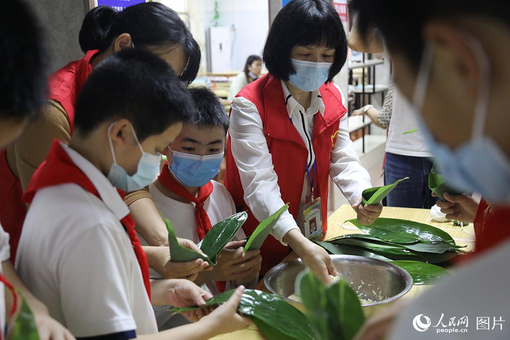 5月31日，在江西省南昌市灣裡四小的教室裡，志願者正在教孩子們包粽子。通過互動活動，讓留守兒童度過了一個溫馨難忘的節日。人民網 時雨攝