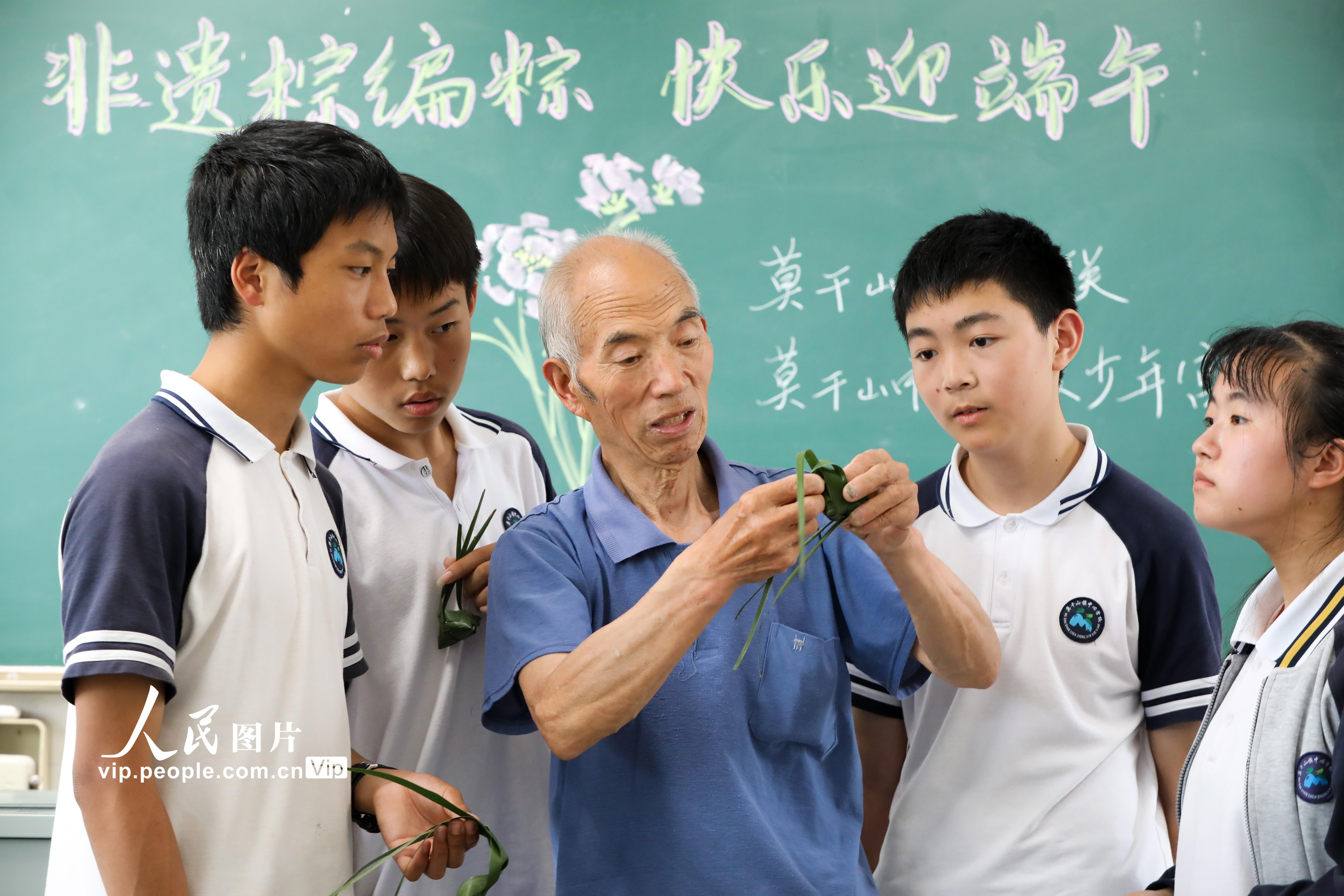 2022年6月2日，浙江省湖州市德清縣莫干山鎮中心學校的學生在校園裡學非遺棕編包粽子。