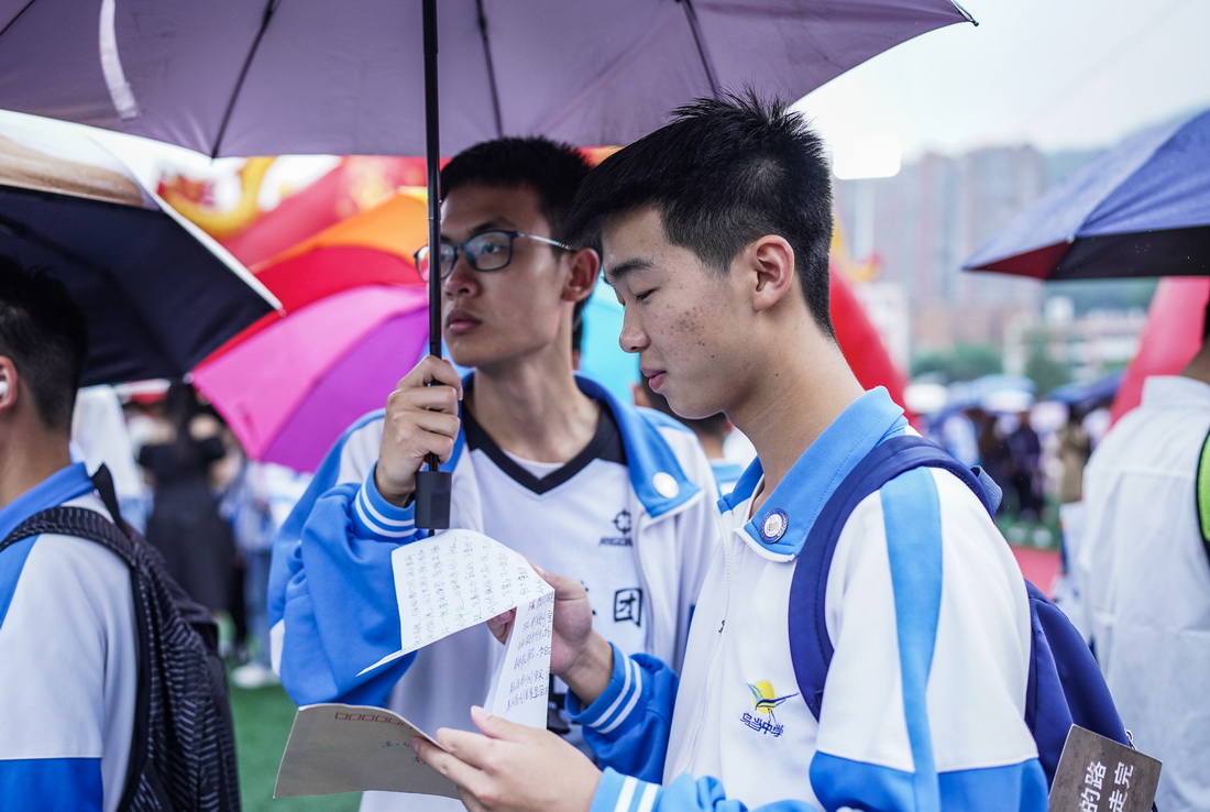 6月9日，贵阳市乌当中学高三学生在雨中阅读父母写给他的信。