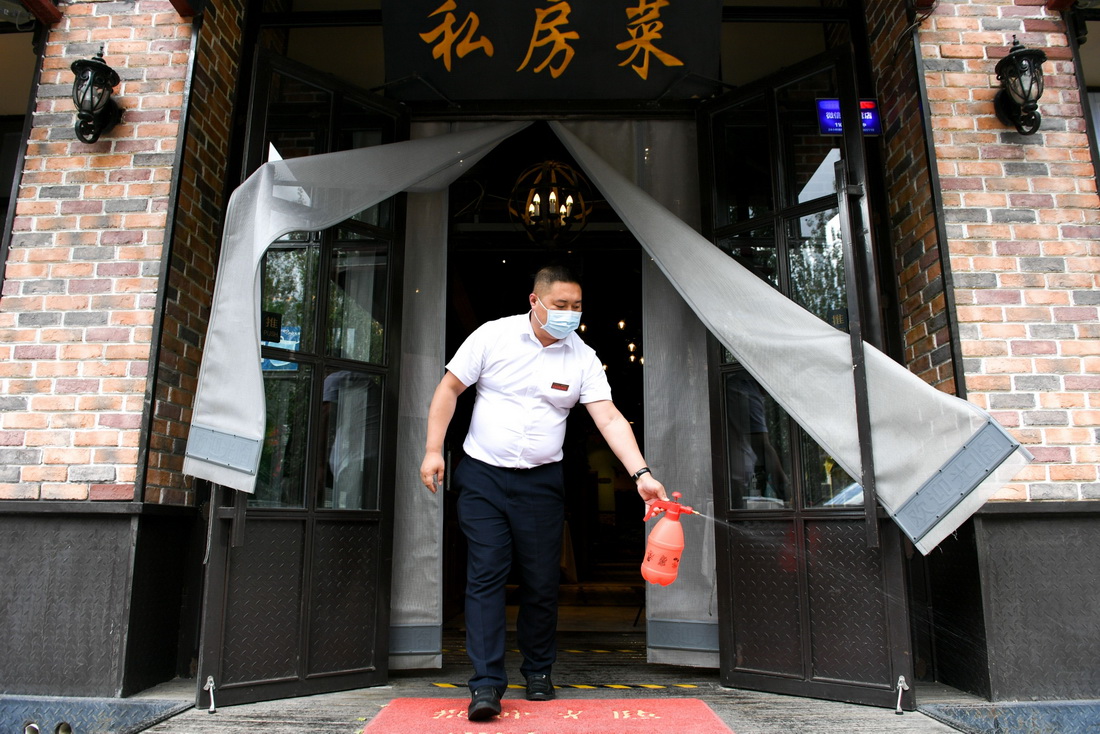 6月13日，呼和浩特市賽罕區一家餐廳的經營者在門前噴洒消毒液。