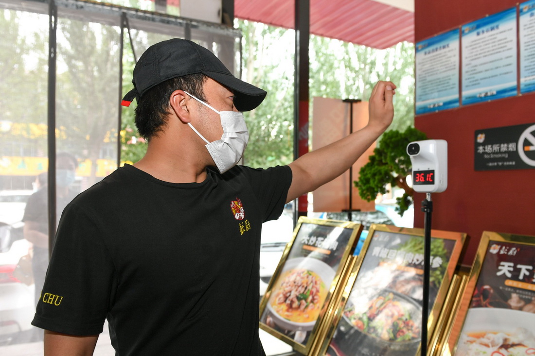 6月13日，在呼和浩特市賽罕區一家餐廳外，餐廳服務人員在開餐前測量體溫。