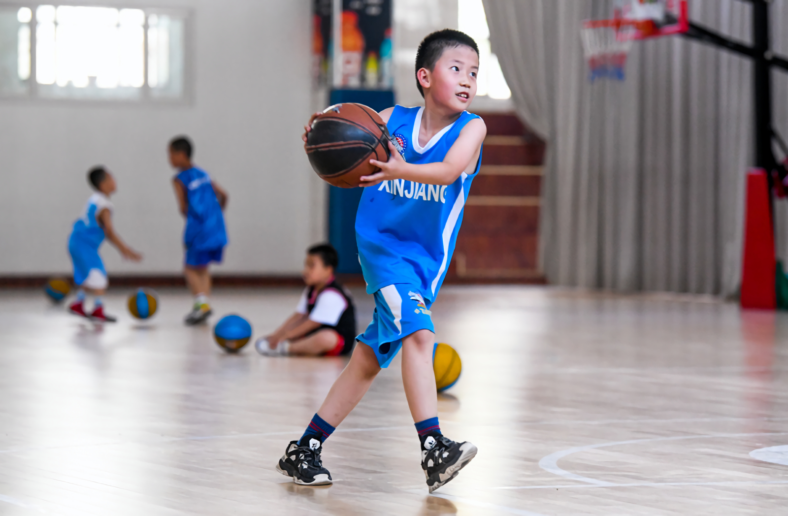 6月18日，在新疆广汇小飞虎篮球训练营内，来自乌鲁木齐市第十三小学一年级5班的于淼翰轩在练习打篮球。