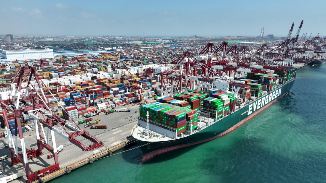 山东港口青岛港前湾港区，集装箱货轮在码头装卸集装箱（6月15日摄，无人机照片）。