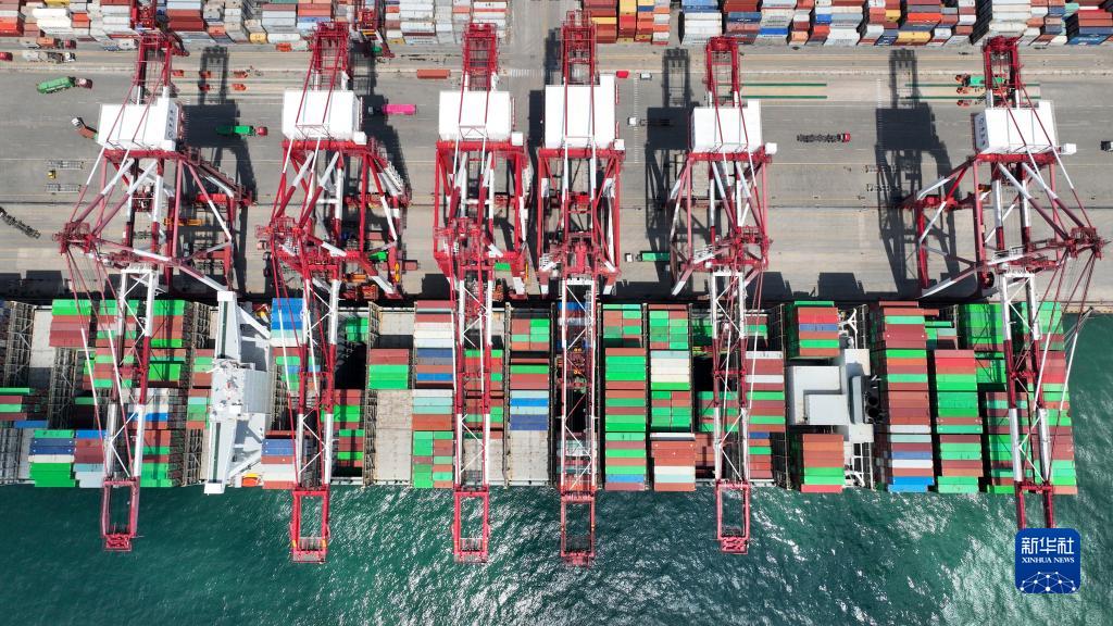 山东港口青岛港前湾港区，一艘集装箱货轮在码头装卸集装箱（6月15日摄，无人机照片）。