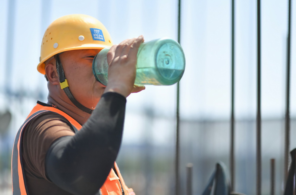 6月23日，在西安浐灞生態區一處安置房項目施工現場，中建三局西北公司工人在工作間隙飲水。