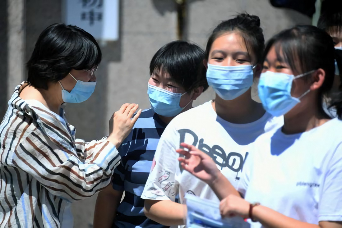 6月24日，考生在结束语文考试后走出北京市平谷区第三中学考点与老师（左一）交流。