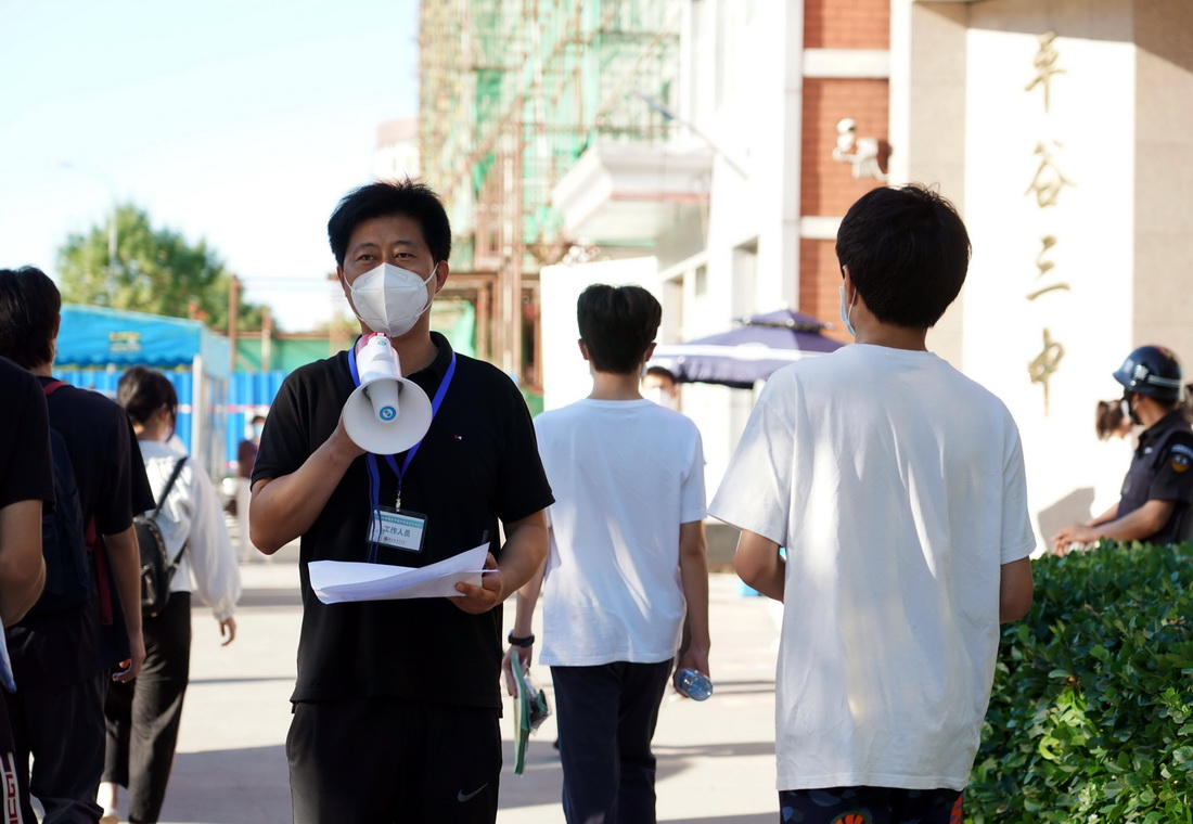 6月24日，考务人员在北京市平谷区第三中学考点外引导考生进入考点。