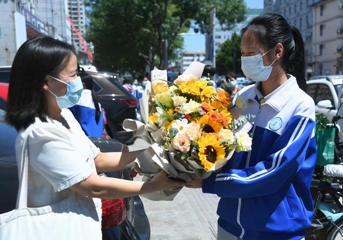 6月24日，在北京市平谷区第三中学考点外，一名考生家长为考生送上鲜花。