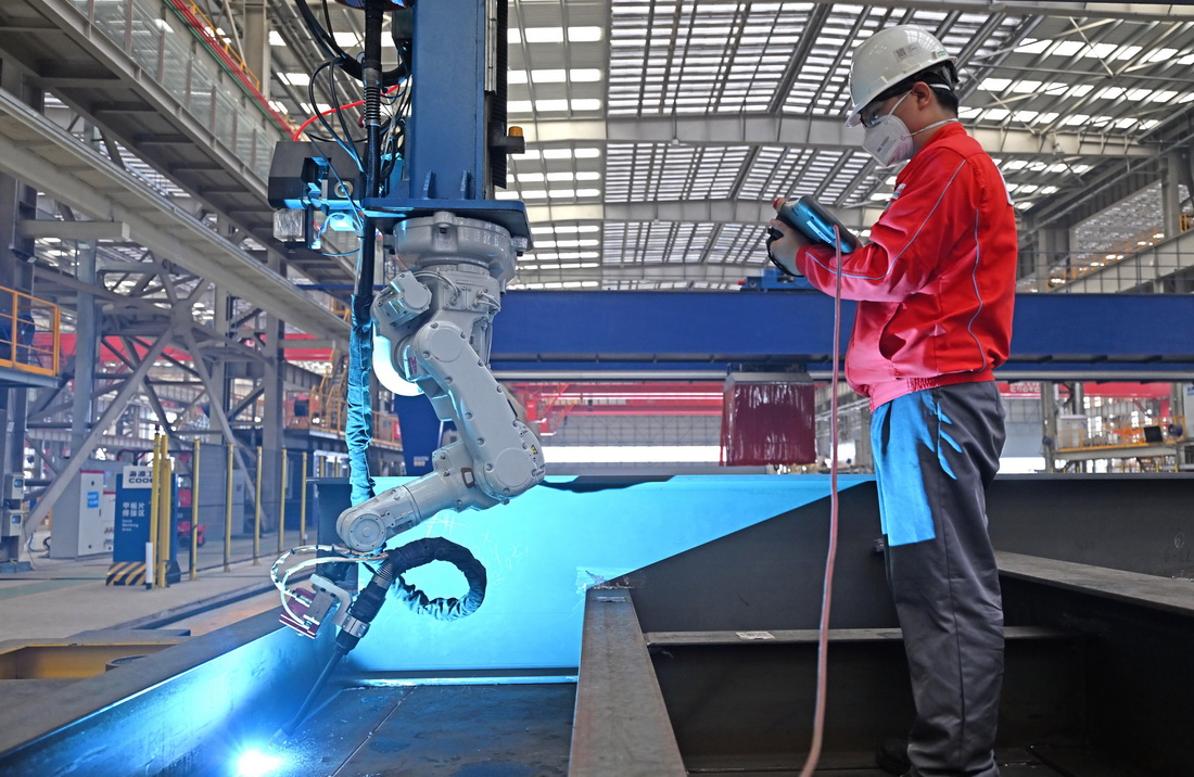 6月26日，在海油工程天津智能化制造基地結構預制車間內，工作人員在操作焊接機器人。