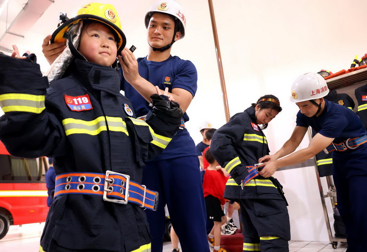 7月5日，消防员协助小学生穿戴消防战斗服。