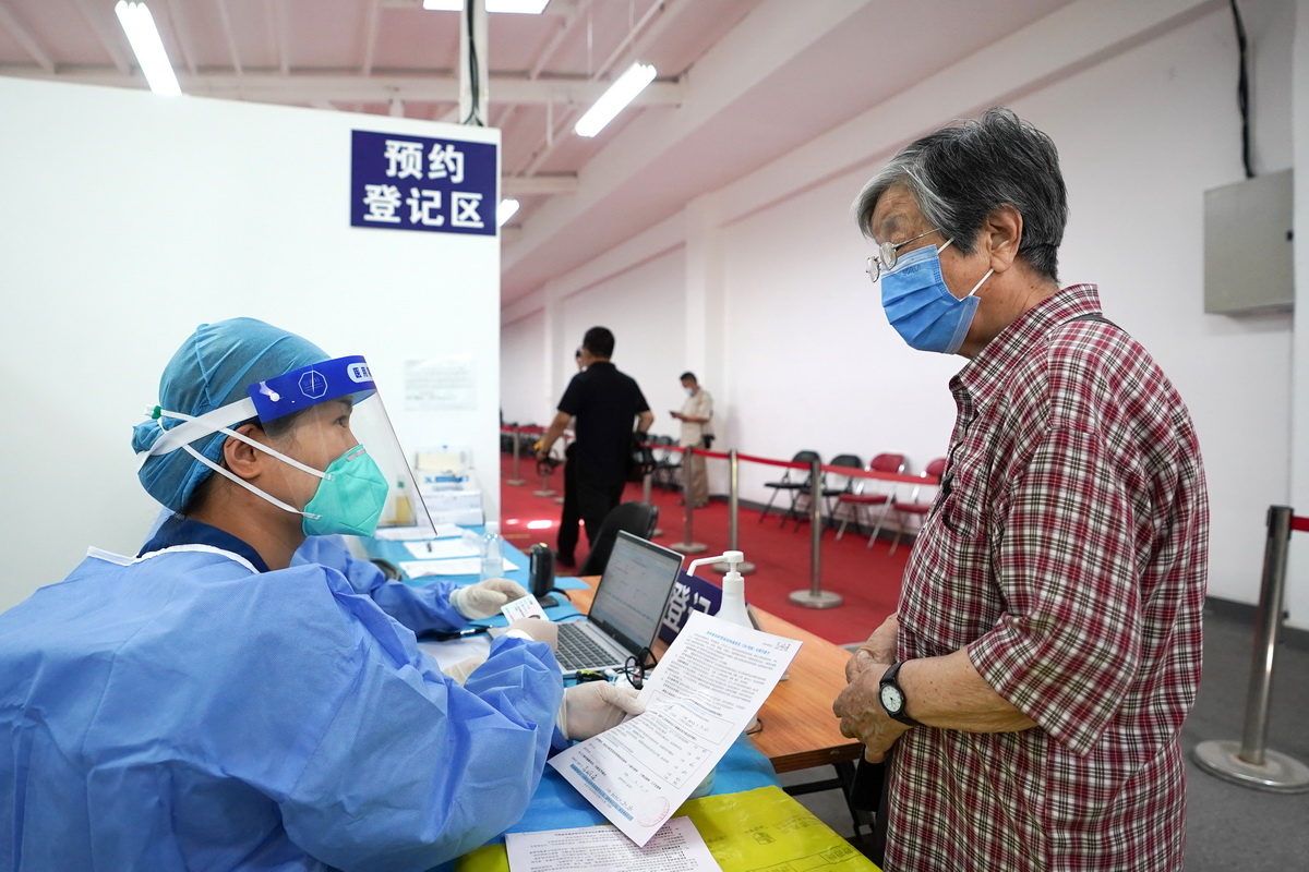 7月13日，在北京市朝阳区奥运村街道一处新冠疫苗接种点，工作人员（左）为一位接种新冠疫苗加强针的86岁市民登记信息。