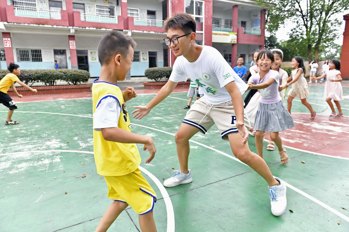 在江西省南昌市灣裡管理局羅亭鎮義坪小學，大學生志願者和留守兒童一起做游戲（7月19日攝）。