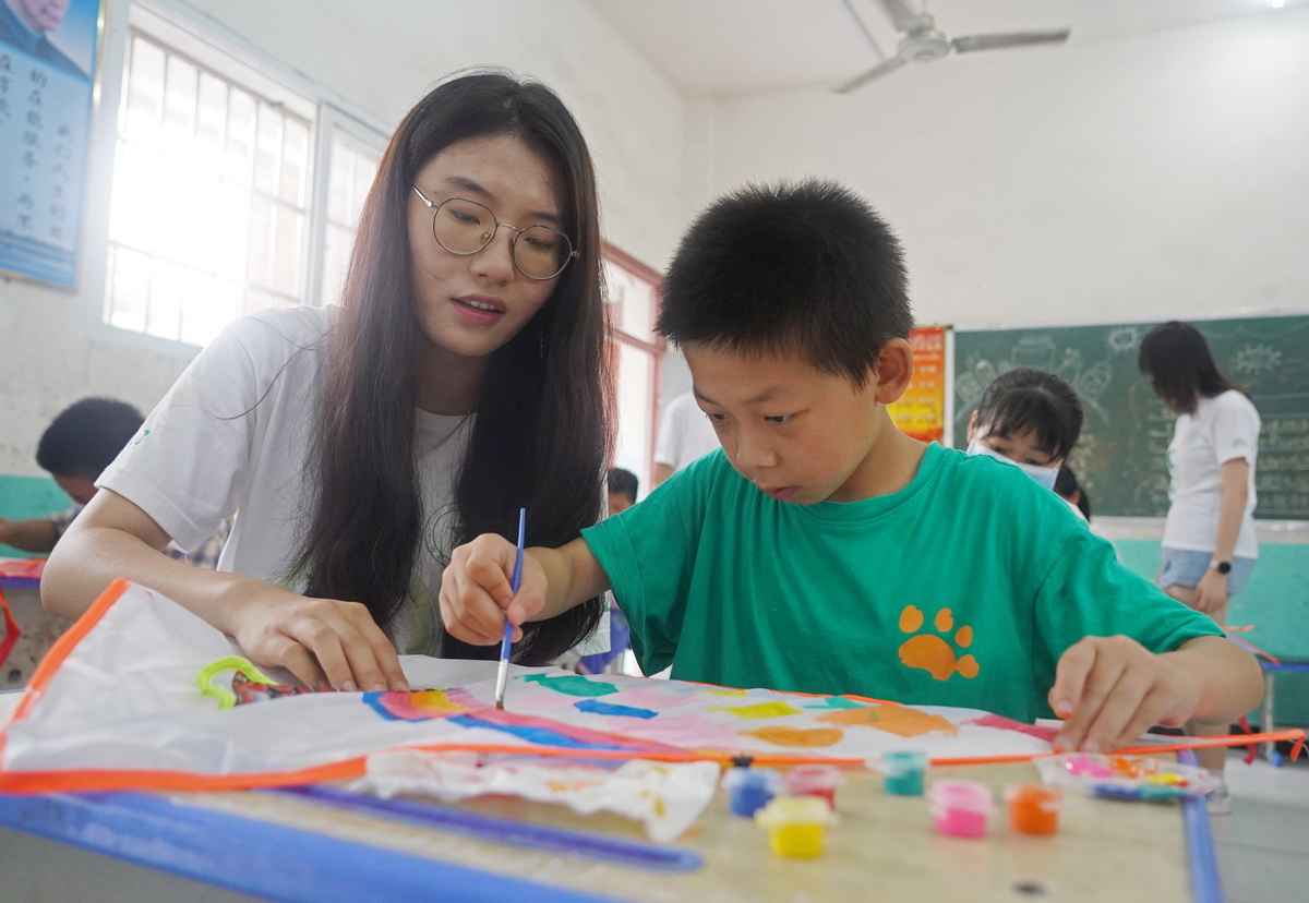 在江西省南昌市灣裡管理局羅亭鎮義坪小學，大學生志願者和留守兒童一起繪制風箏（7月19日攝）。