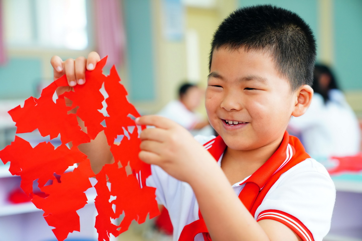 7月28日，在山東省齊河縣祝阿鎮馬坊社區鄉村“復興少年宮”，一名小朋友展示自己的剪紙。
