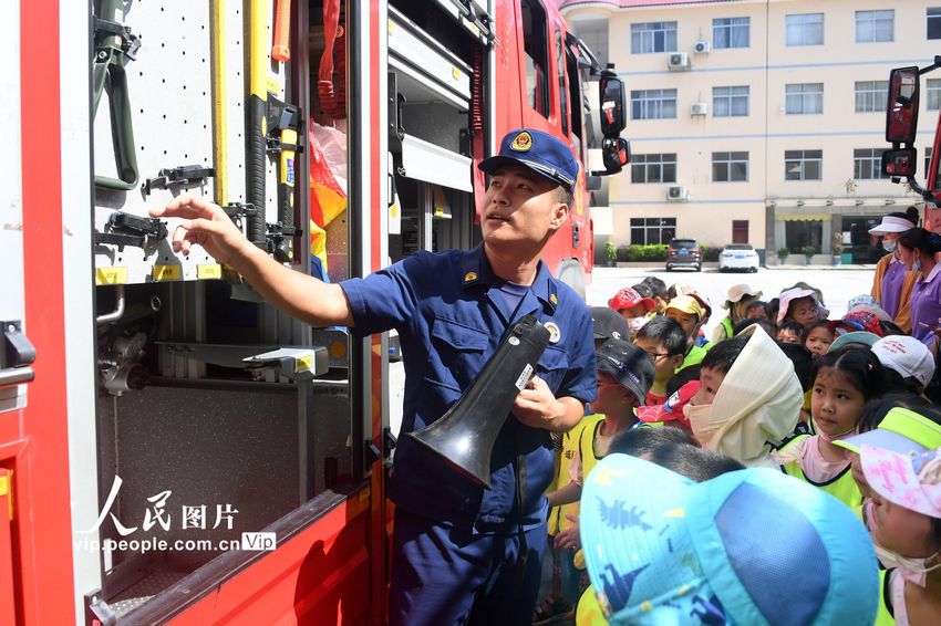 2022年8月8日，在广西河池市罗城仫佬族自治县消防救援大队，消防员在向孩子们介绍消防器材功能和使用方法。