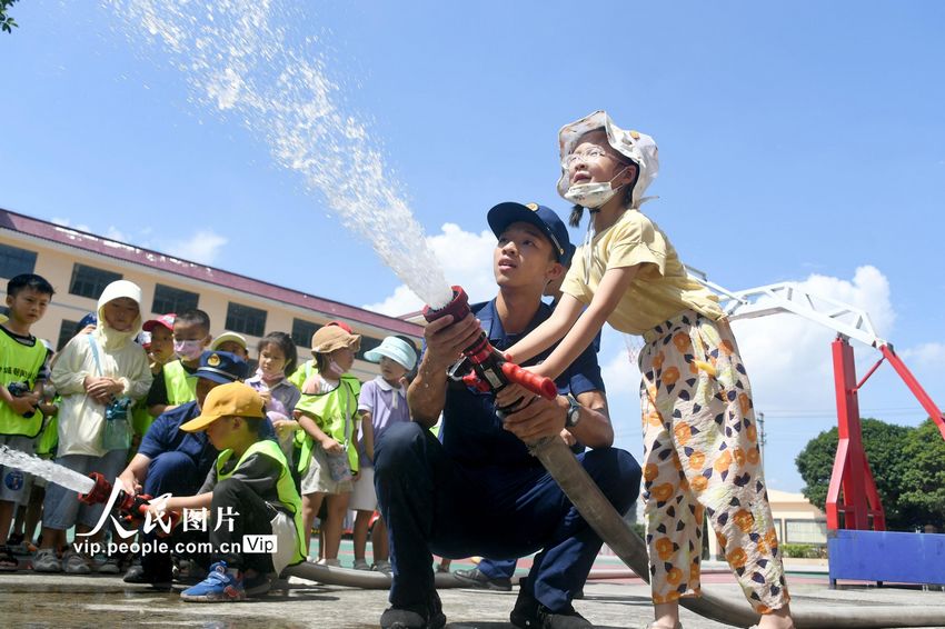2022年8月8日，在广西河池市罗城仫佬族自治县消防救援大队，消防员带着孩子们体验水泵灭火操作使用。