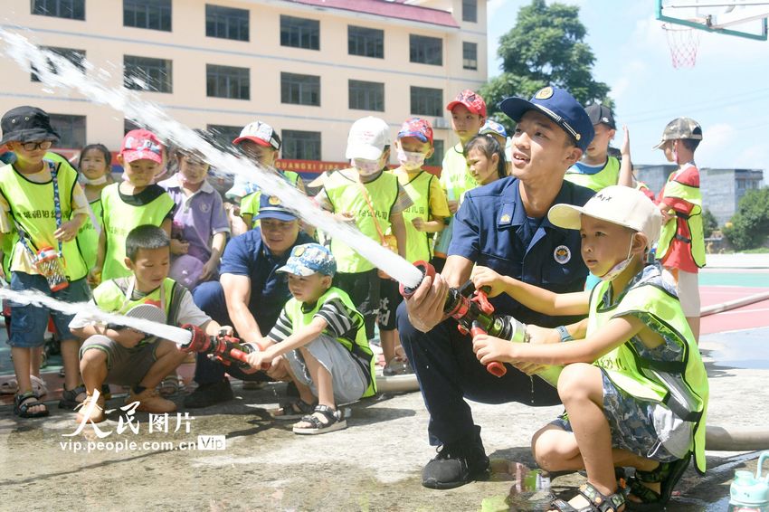 2022年8月8日，在广西河池市罗城仫佬族自治县消防救援大队，消防员带着孩子们体验水泵灭火操作使用。