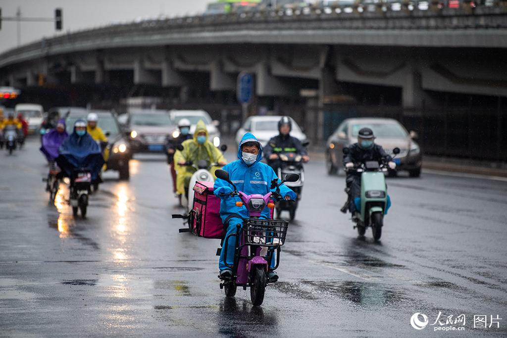 8月9日早高峰，骑车人冒雨骑行。人民网记者 翁奇羽摄