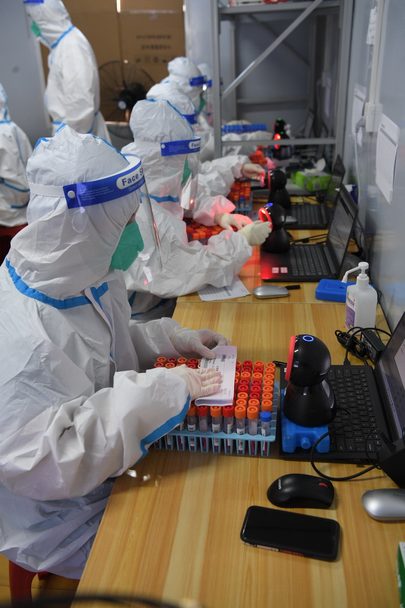 8月14日，在三亞市美麗之冠大劇院的核酸檢測實驗室，檢測員對核酸樣本掃碼。