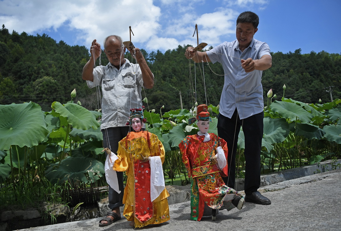 在江西省广昌县塘坊镇淇田村，木偶剧团团长谢帮银（右）和同事一起练习木偶表演动作（8月10日摄）。