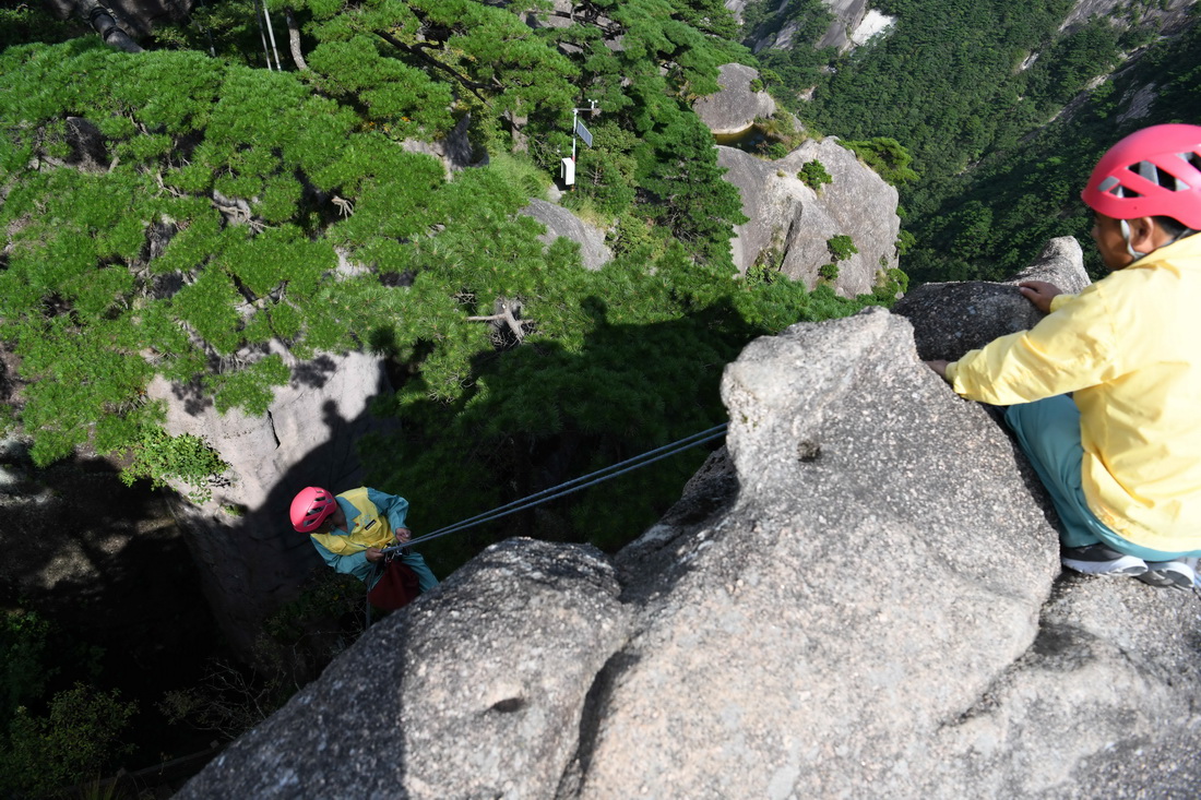 8月15日，李培生（左）在黃山風景區的懸崖峭壁間清撿垃圾。新華社記者 周牧 攝