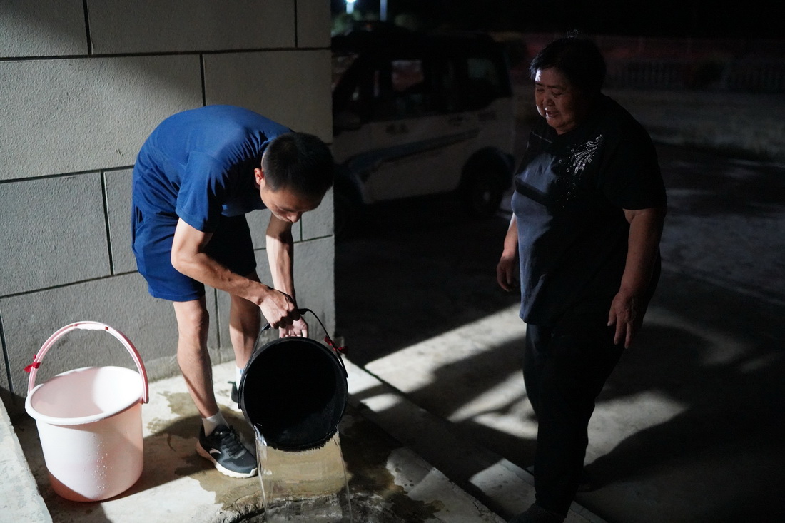 在瑞昌市范鎮上源村，消防員傅康（左）幫一名老人提水回家（8月23日攝）。