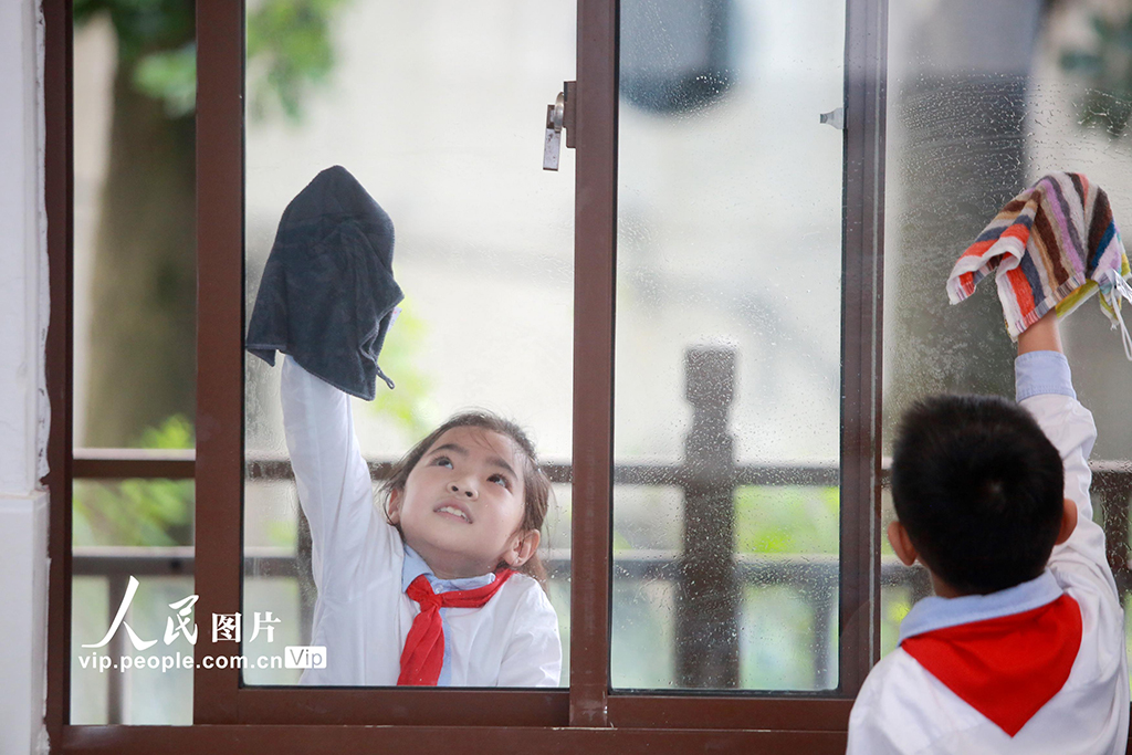 9月1日，江苏省扬州市汶河小学北柳巷校区的学生在清洁教学楼的玻璃窗。孟德龙/人民图片 